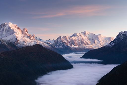 Summer landcsape view of a foggy valley at sunset with an illuminated mountain range