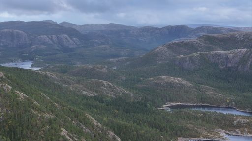 A scenic view of a mountainous landscape with lush greenery and small lakes under a cloudy sky.