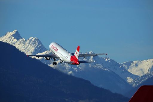 Departing Austrian Airbus A320 with snowy mountains in the backgroun