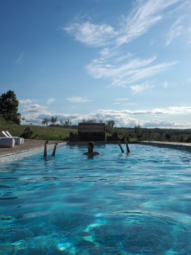 A vertical shot of a Caucasian man in the pool with two upside-down women, on a sunny day