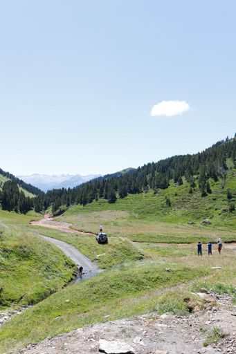 A rural road through the green fields in the mountains on a sunny day