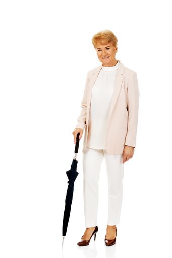 A senior elegant Caucasian female wearing white and holding an umbrella on a white background
