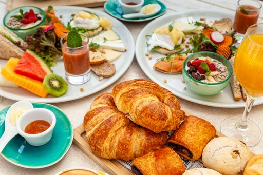 A high angle shot croissants, different pastries with orange juice, and other tasty snacks beautifully arranged on a table