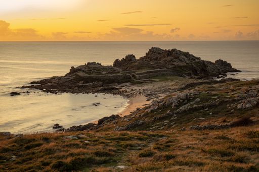 The mesmerizing view of the shore of the calm ocean during sunset in Galicia, Spain