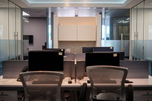 Modern office with computer desks and glass partitions, showcasing a clean and organized environment.