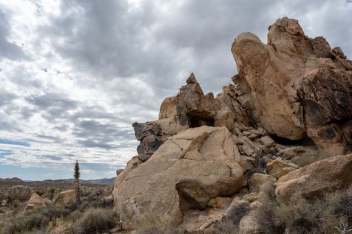 A rocky landscape under a cloudy sky in Joshua Tree National Park, California.