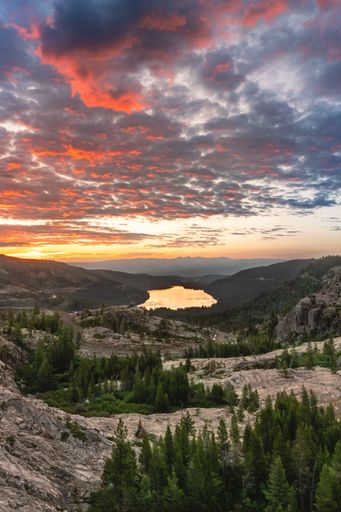 A breathtaking sunset over Donner Lake in California with a dramatic sky and lush green forest.