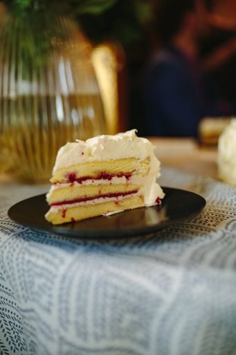A vertical closeup shot of a wedding cake slice with layers and strawberry filling on the table