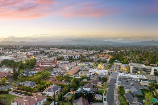 Aerial view of a suburban neighborhood during sunset with a mix of residential and commercial buildings, and mountains in the background.