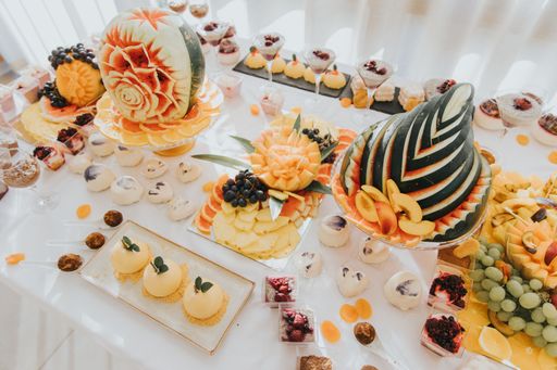 A beautifully arranged table of carved fruits and desserts, with detailed watermelon carvings
