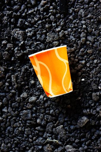 A top view of an orange paper cup laid on a rocky ground