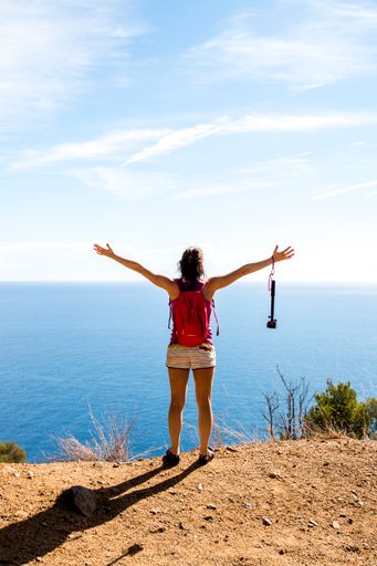 A vertical back view of a hiker enjoying the view over the sea