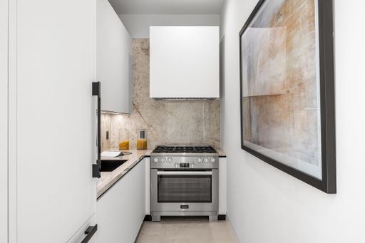 Modern minimalist kitchen with a sleek design, featuring stainless steel appliances and white cabinetry.