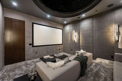 A modern home theater room with a large screen, comfortable seating, and ambient lighting.