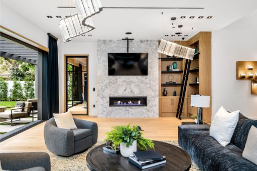 Modern living room interior with stylish furniture, open sliding doors to garden, and a marble fireplace with a TV above.