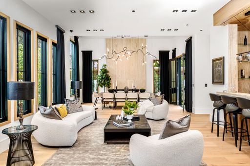 Modern living room with stylish furniture, large windows, and contemporary decor, featuring a dining area and bar counter.