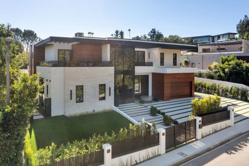 Modern luxury house with large windows and landscaped yard in a suburban neighborhood on a sunny day.
