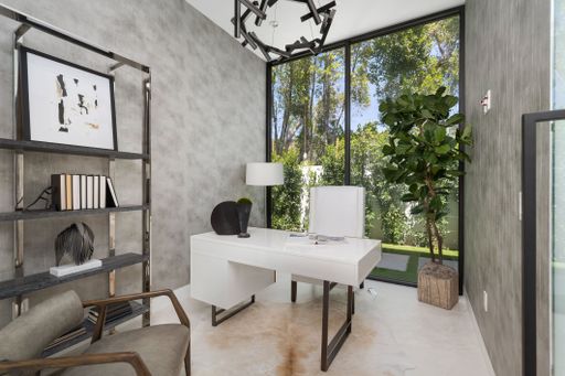 Modern home office with large windows, minimalist decor, and greenery outside.
