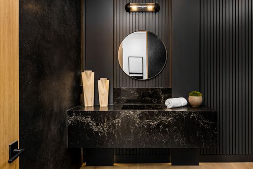 Modern bathroom with black marble sink, round mirror, and wooden decor elements