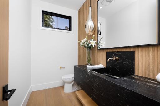 Modern bathroom interior with a black marble sink, wooden accents, and a large mirror.