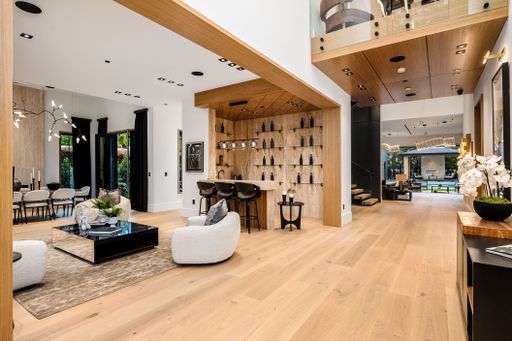 Modern open-concept living area featuring wooden floors, a bar area, and contemporary furniture.