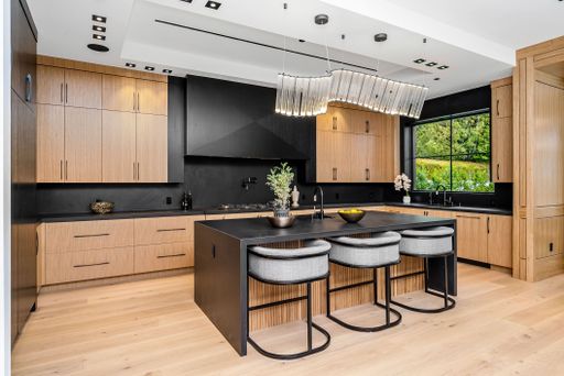 A modern kitchen featuring wooden cabinets and sleek black countertops.
