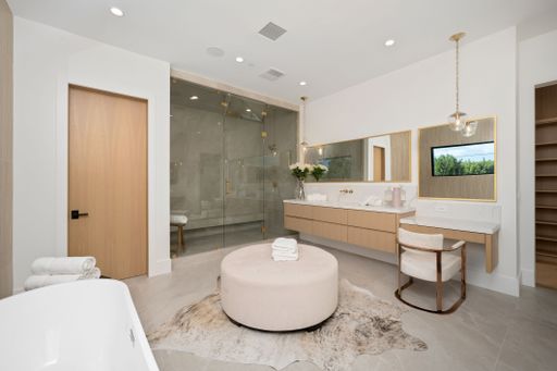Modern bathroom with glass shower, vanity, and stylish decor, featuring a large mirror and natural lighting.