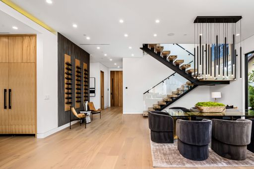 Modern open-concept living room and dining area with a stylish staircase, contemporary furniture, and elegant lighting.