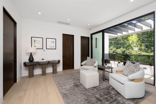 Modern living room interior with contemporary furniture, large windows, and a view of lush greenery outside.