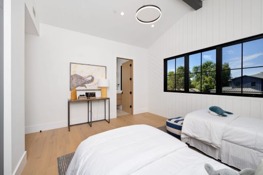 Modern bedroom with twin beds, large windows, and a minimalist decor in a bright and airy interior.