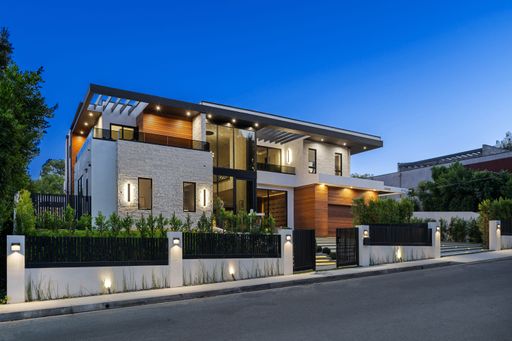 Modern two-story house with a sleek design, illuminated exterior, and landscaped front yard during twilight.