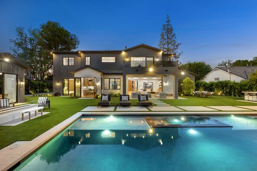 Luxurious modern house with a swimming pool and well-manicured lawn, captured during twilight.