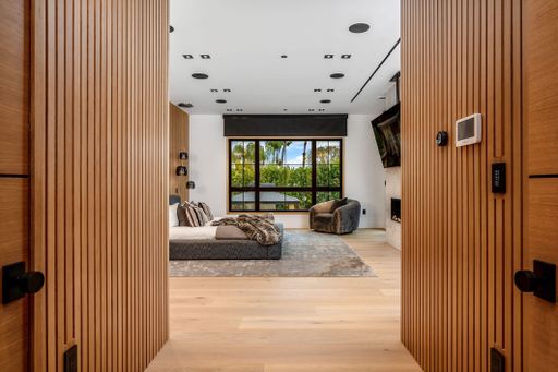 Modern bedroom interior with wooden accents, large window, and cozy seating area.