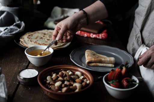 A closeup shot of pancakes served on a plate with strawberries on a wooden table