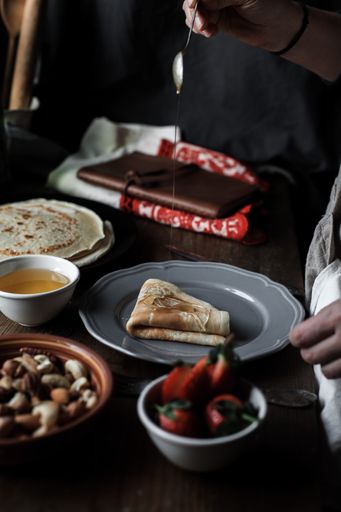A vertical shot of pancakes served on a plate with strawberries on a wooden table
