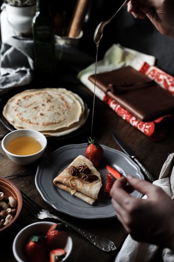 A vertical shot of pancakes served on a plate with strawberries