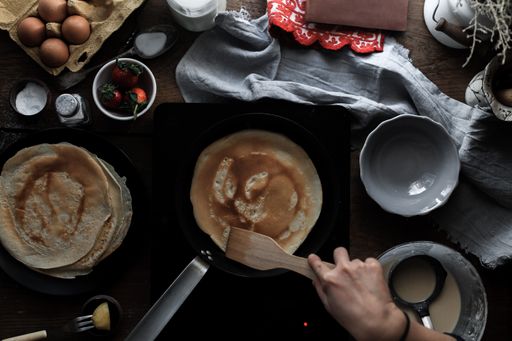 A top view of a woman baking pancakes in the pan