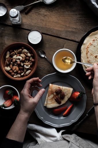 A vertical shot of pancakes served on a plate with strawberries