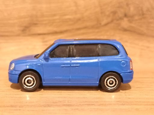 A blue Mattel Matchbox Levc TX Taxi toy model car on a wooden background.