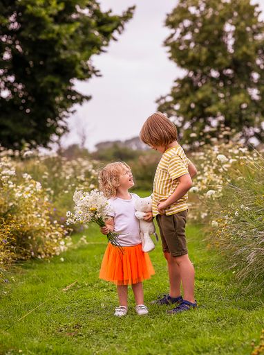 A selective of a young boy walking in the forest with his little sister