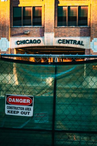 Construction site with a 'Danger' sign in front of Chicago Central building during sunset