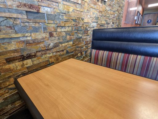 A table next to a slate multicolor wall in a cafe