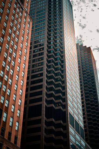 A low angle vertical view of the skyscraper of CME Group Financial company with glass windows against cloudy sky in Chicago, USA
