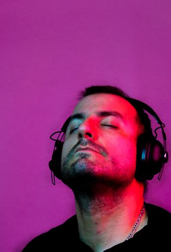 A Neon portrait of a man wearing sunglasses and with headphones listening to music