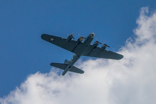 A military airplane flying high in the cloudy sky