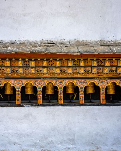 The traditional Buddhist prayer wheels against a white wall. Punakha Dzong, Bhutan.