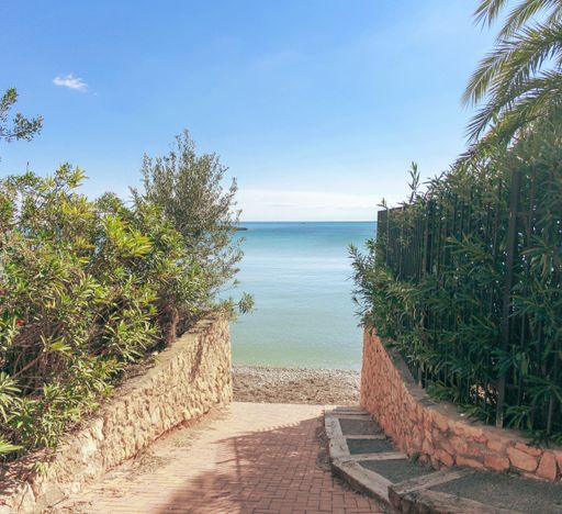 A small path through gardens leading to the sea