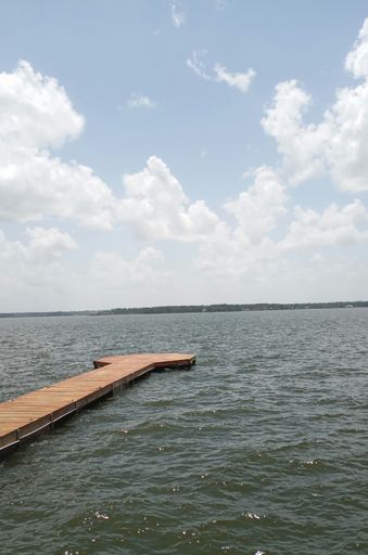 A vertical shot of wavy water with a wooden pier under a cloudy sky
