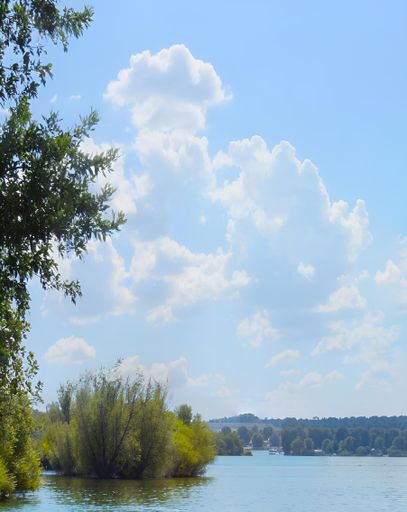 A scenic view of a lake surrounded by lush greenery and trees under a bright blue sky with fluffy clouds.