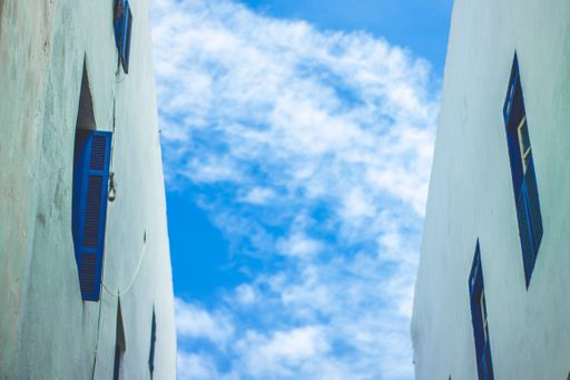 A view of the sky framed by two buildings with blue windows, creating a symmetrical composition.
